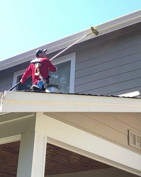 Technician polishing gutters to remove stuck on dirt and leave gutters looking like new. This service can be combined with annual roof cleaning by Valentine Roofing.